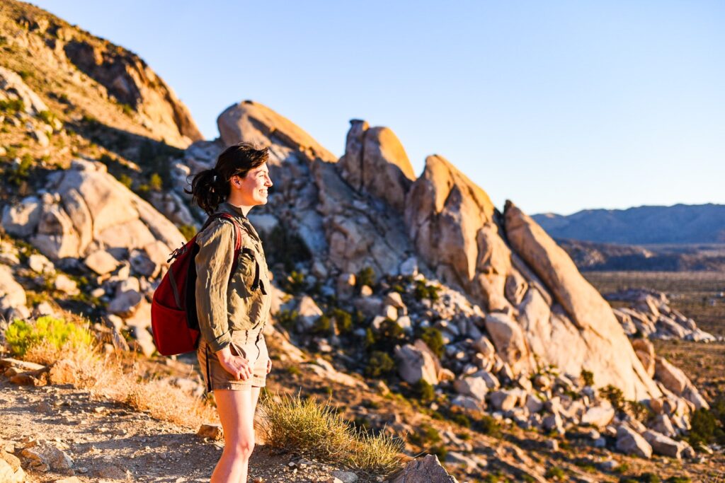 Female hiker looks out at sunset over valley