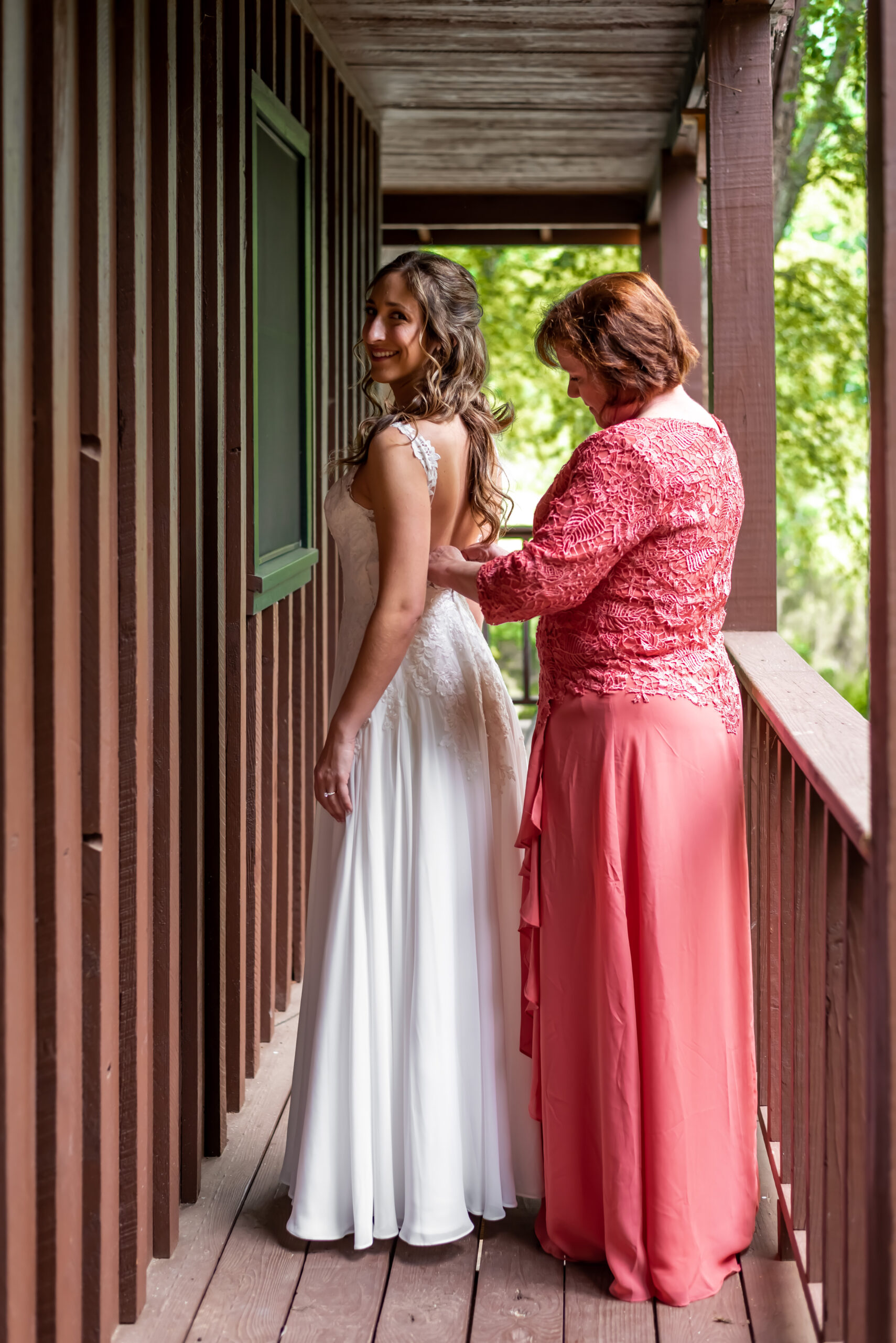 Mother of bride helps button her daughter's wedding dress