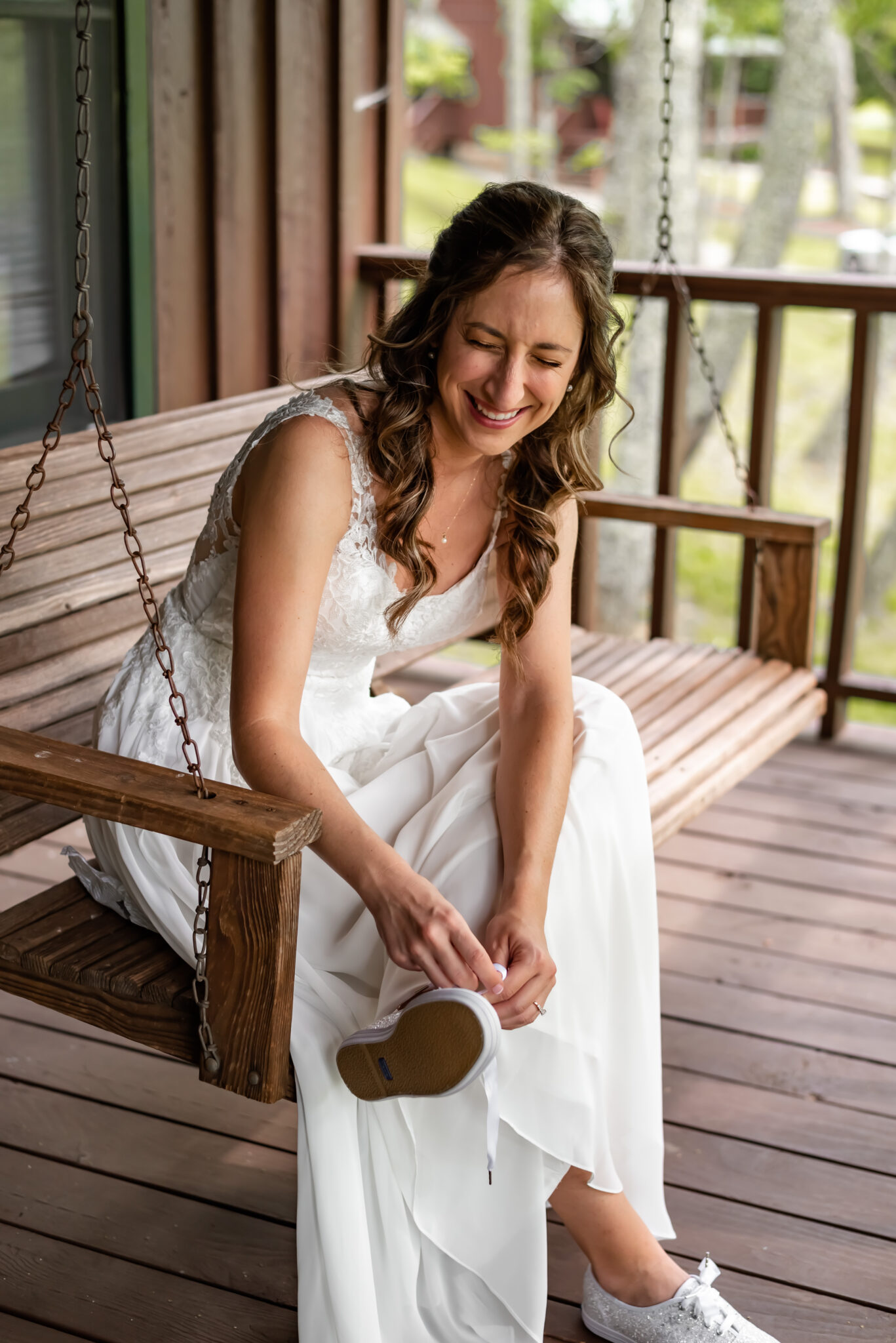 Bride giggles as she puts on sparkly Keds for her wedding 