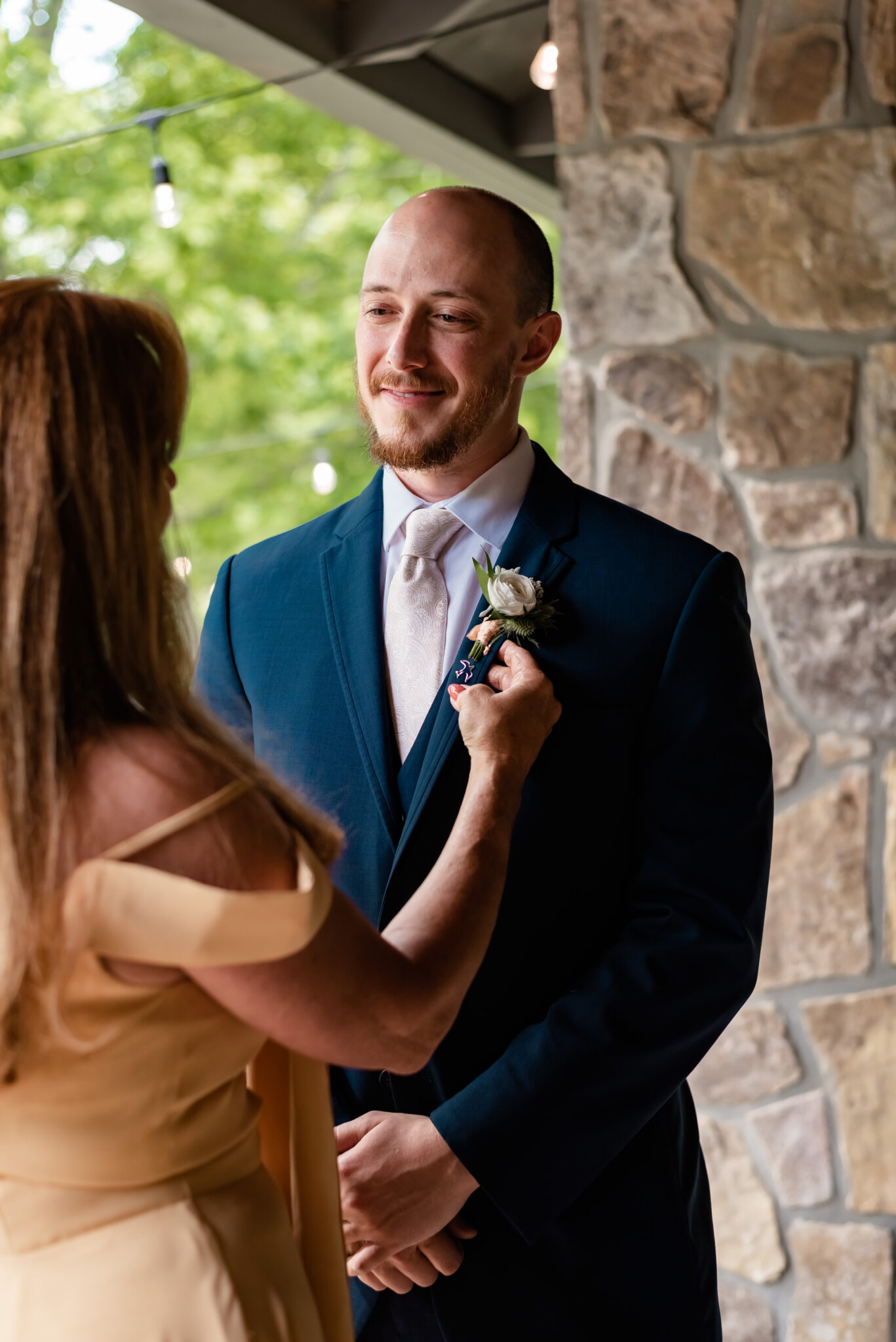 Mother of groom puts his boutonniere on 