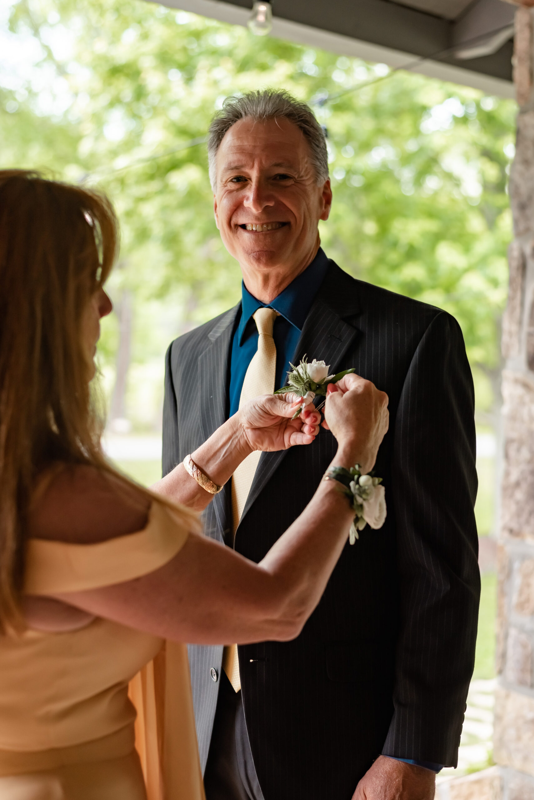 Mother of groom helps father with boutonniere