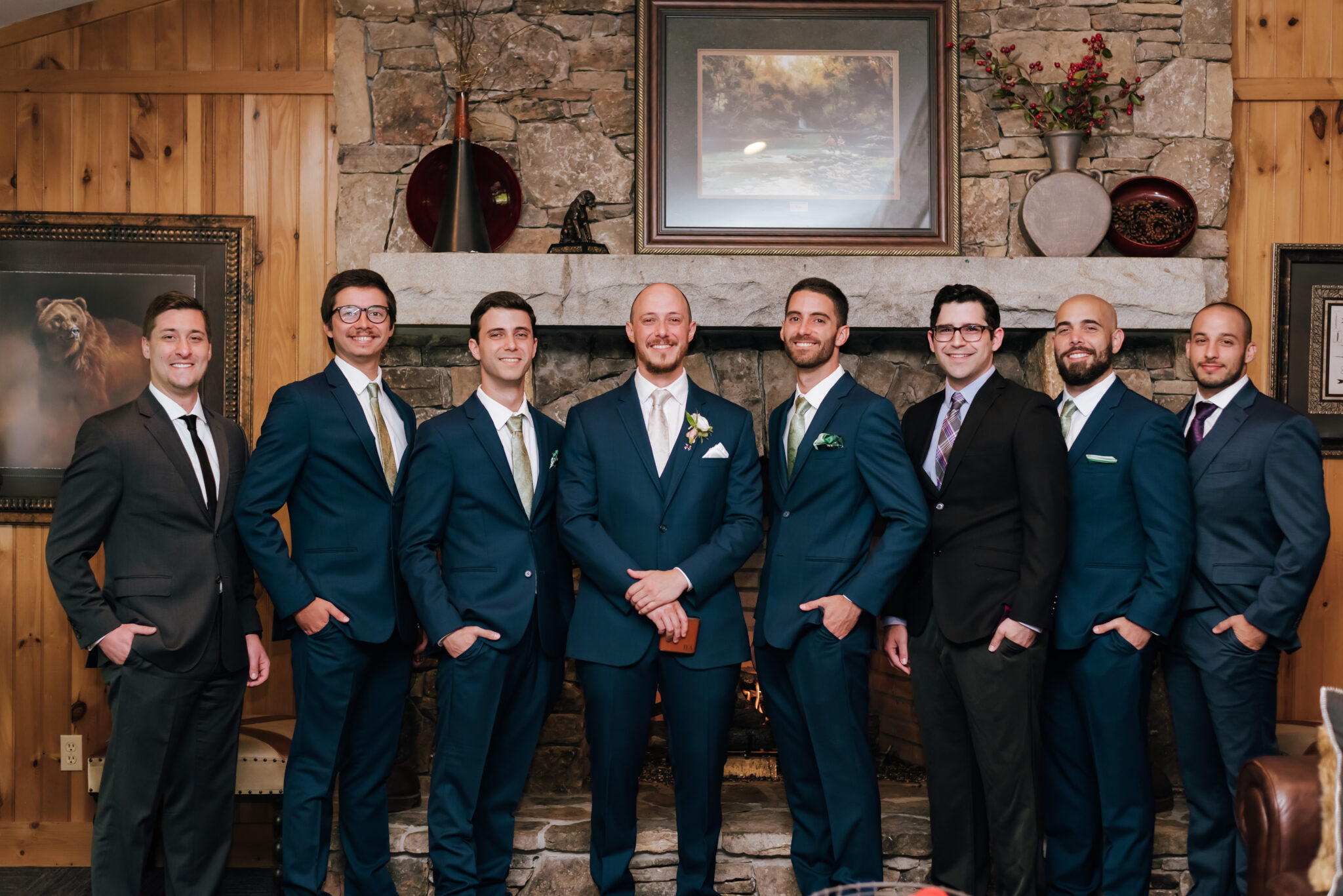 Groomsmen pose in front of rustic fireplace