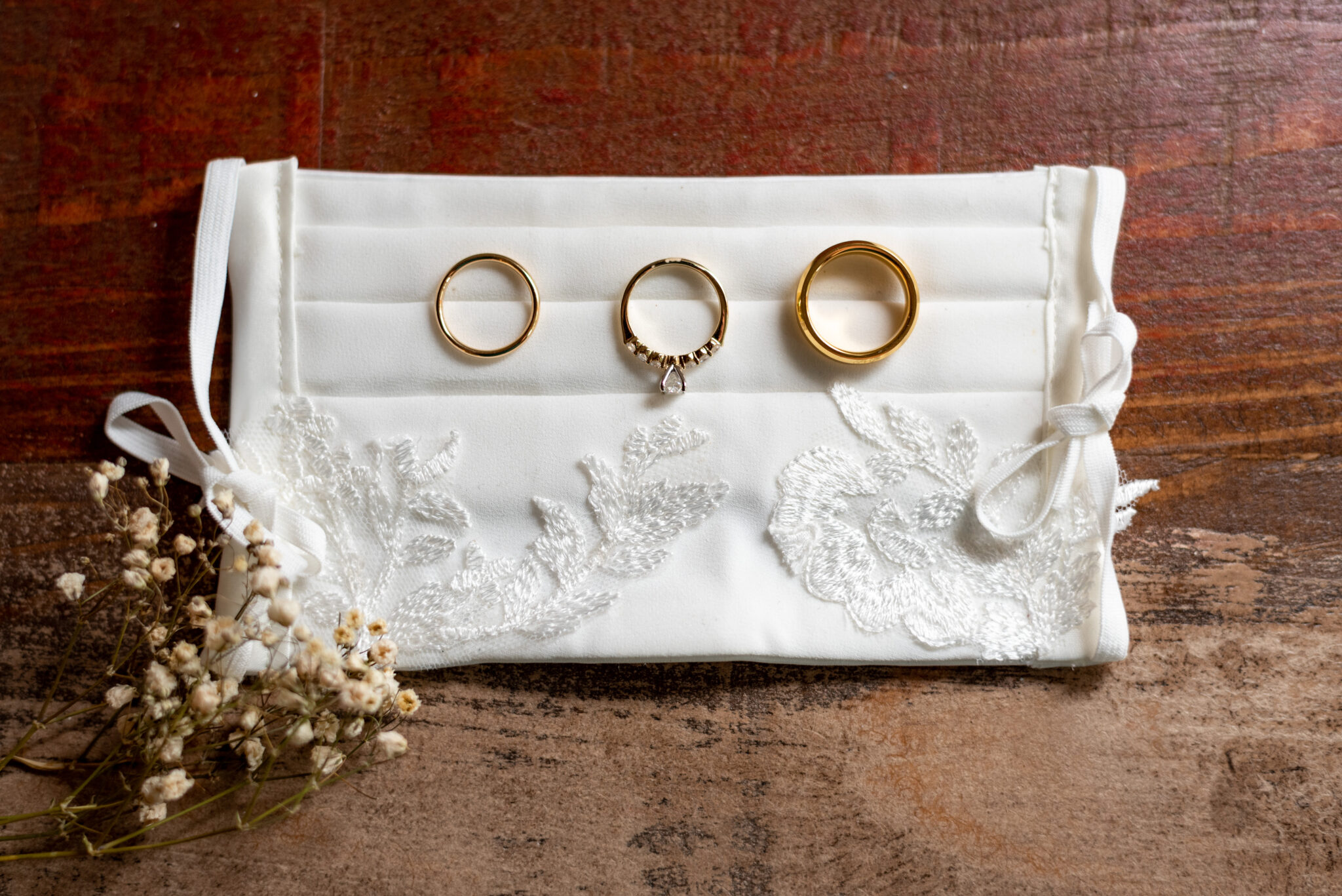 three gold wedding bands sit atop a white bridal mask