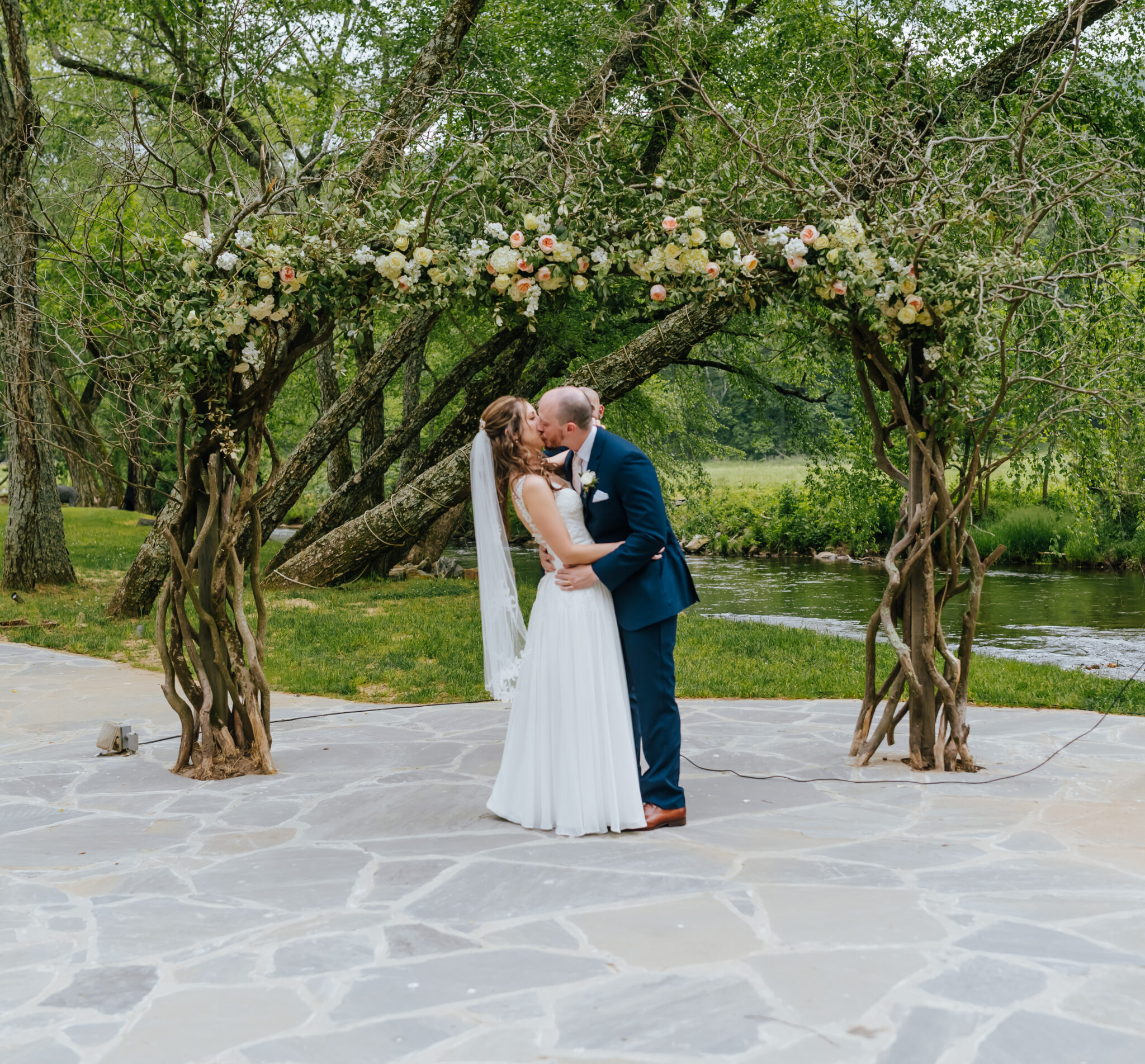Bride and groom kiss in front of floral arch