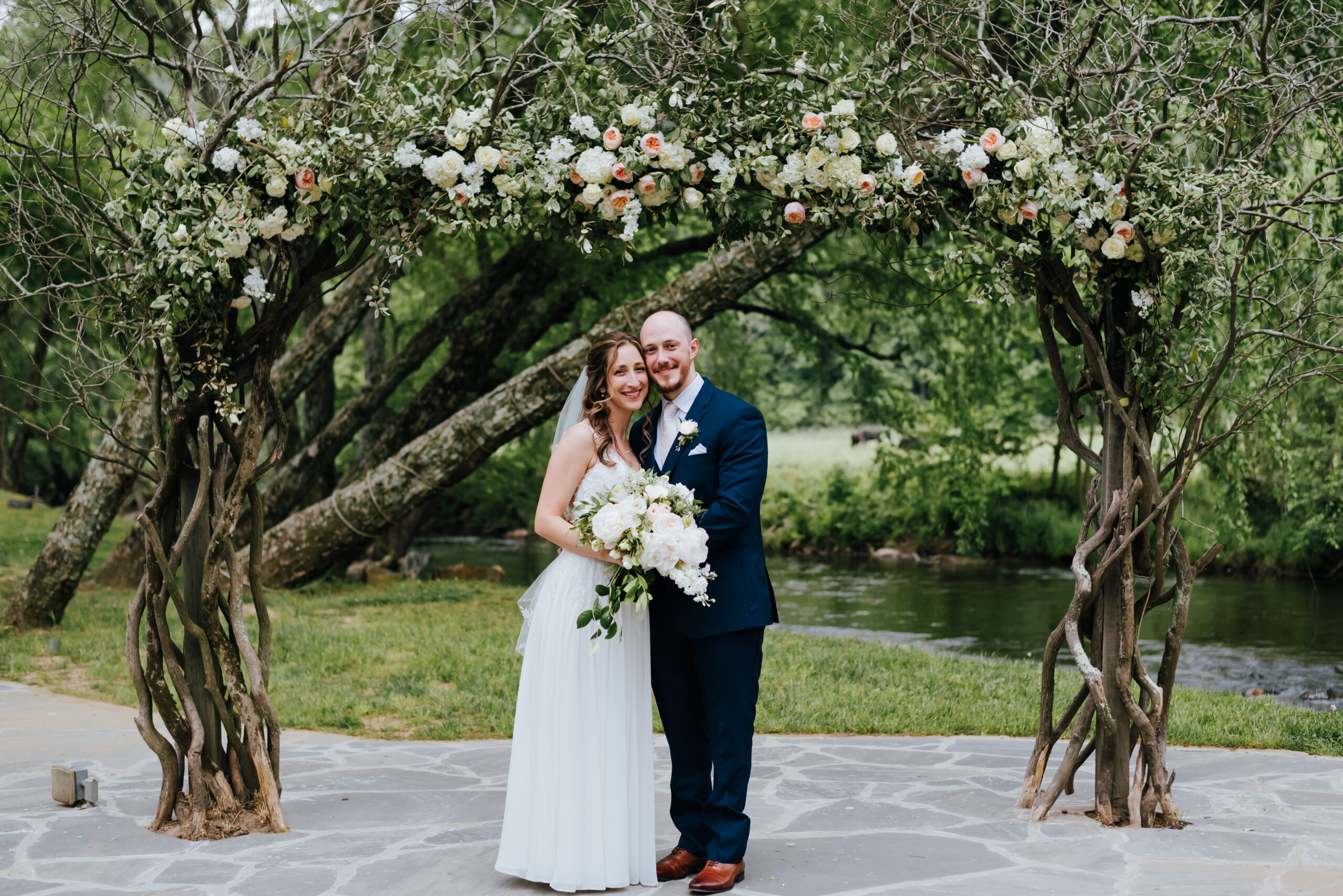 Newlyweds stand under flower arch at Hiawassee River