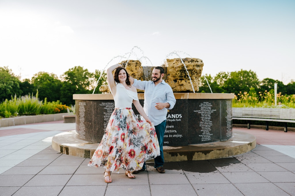Couple twirls in front of a fountain