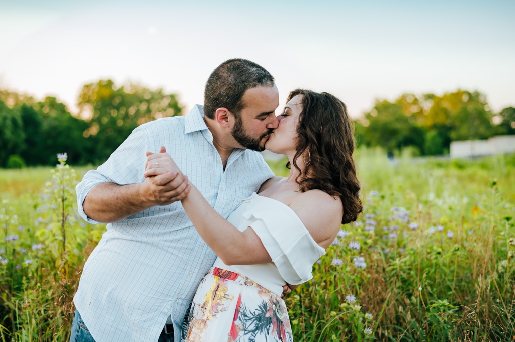 Man dips his fiancee for a kiss in a beautiful field of wildflowers