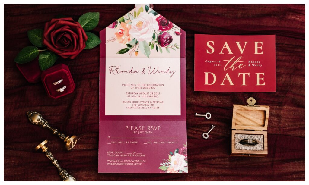 A photography of a burgundy themed invitation suite and wedding rings