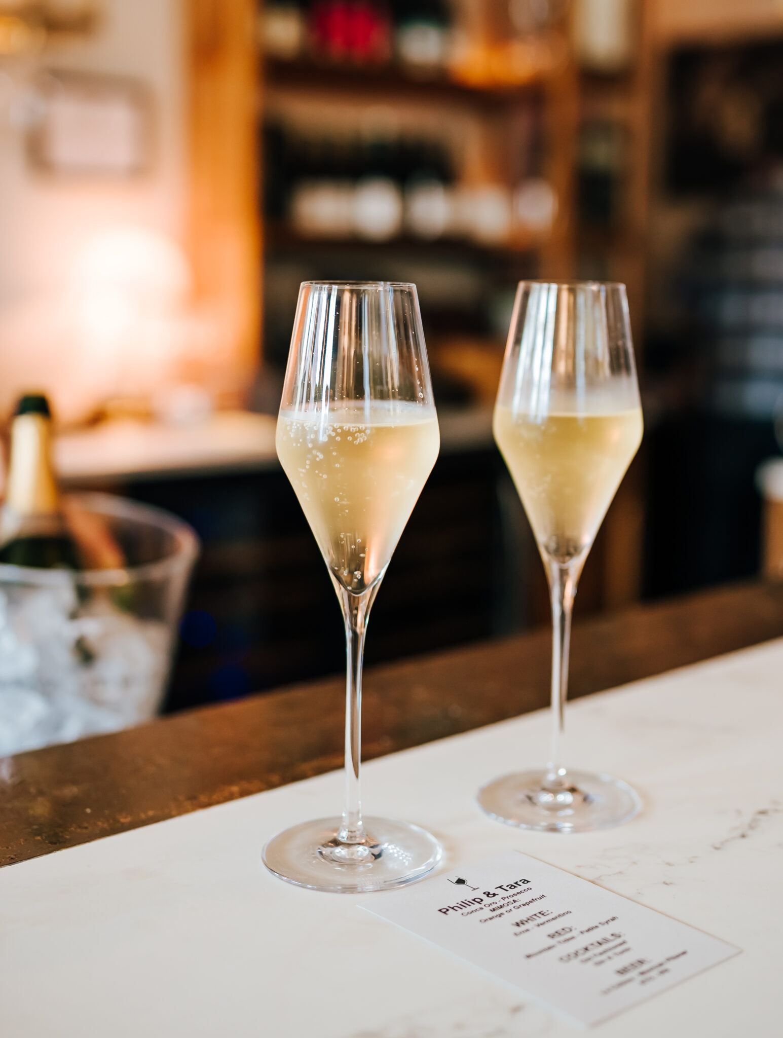 A photograph of two glasses of champagne at the bar