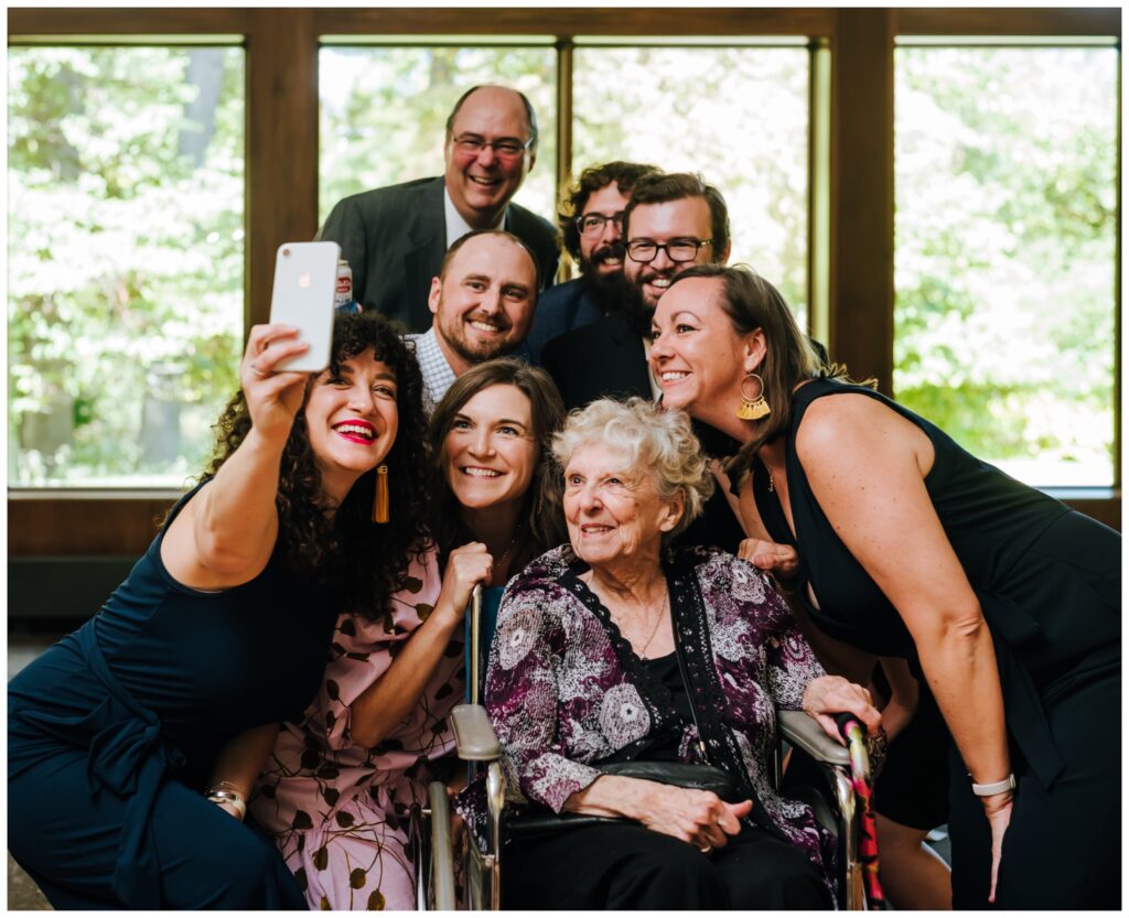 A family takes a selfie with their grandmother in her wheelchair