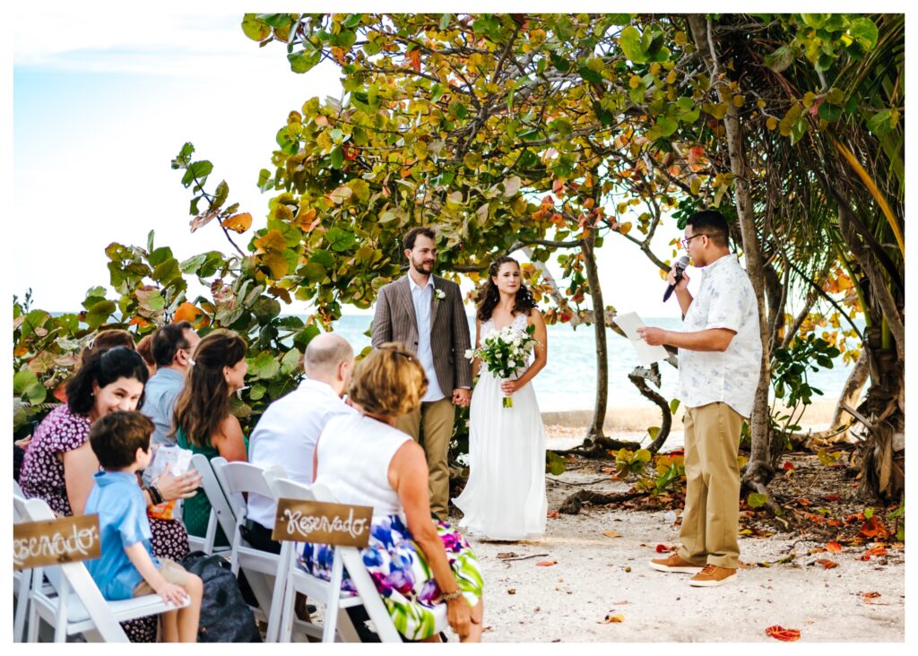 Couple stands in front of tropical trees during ceremony