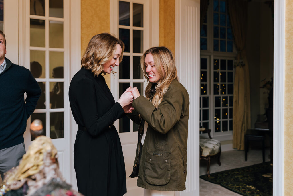 The newly engaged woman shows her sister the ring
