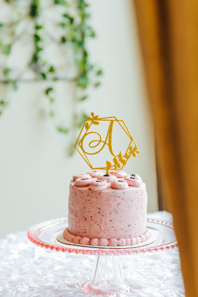 A petite pink cake with a monogrammed A topper