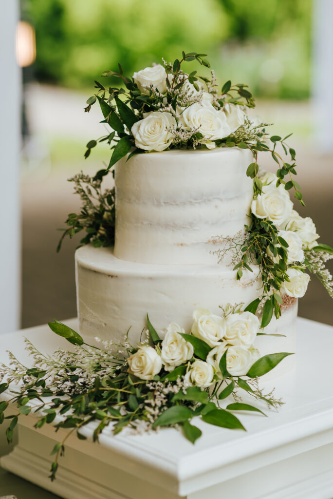 White flowers and greenery adorn a classic white wedding cake