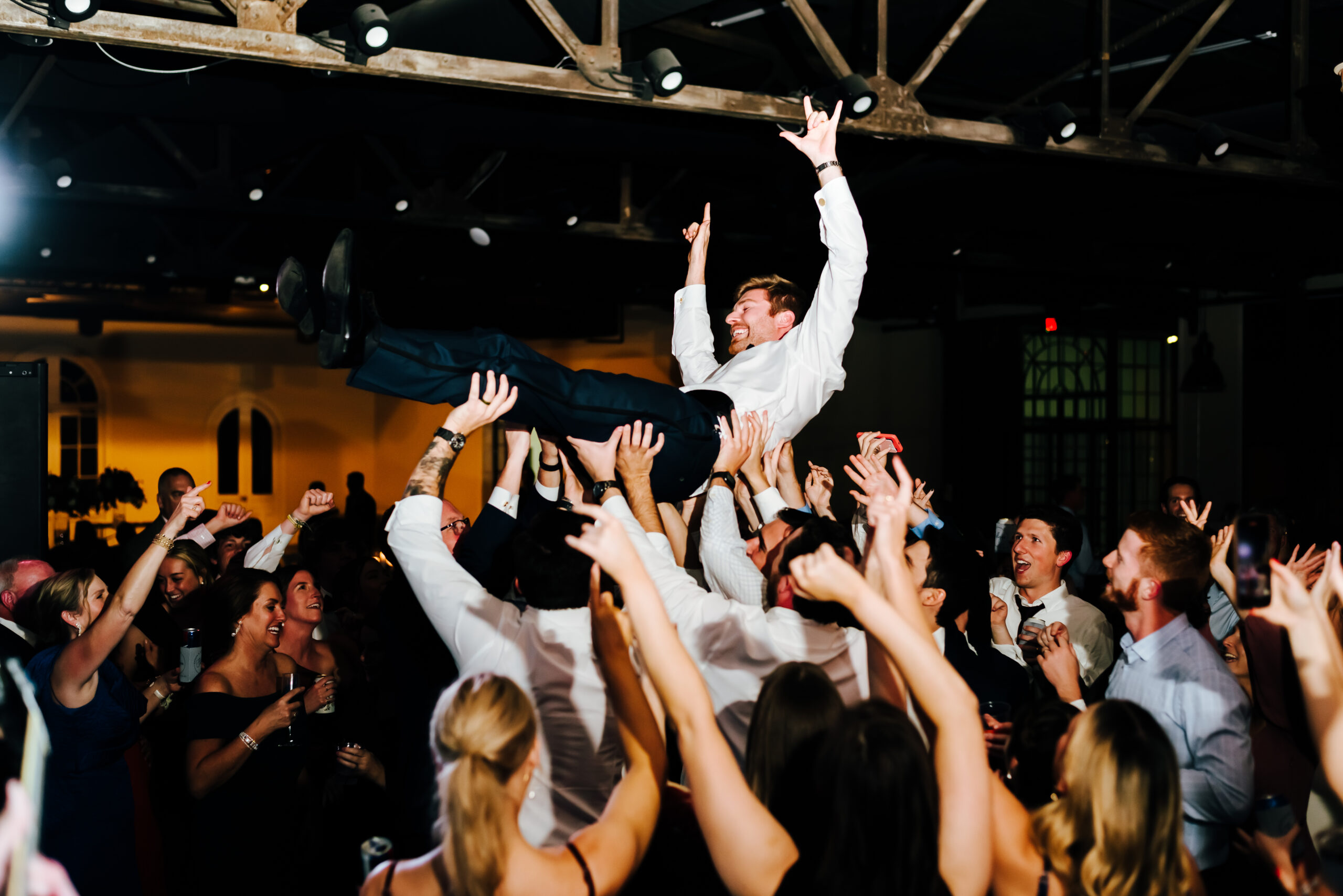 A groom crowd surfs at his wedding reception