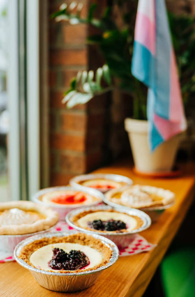 An assortment of Georgia's Sweet Potato Pies in front of the trans flag