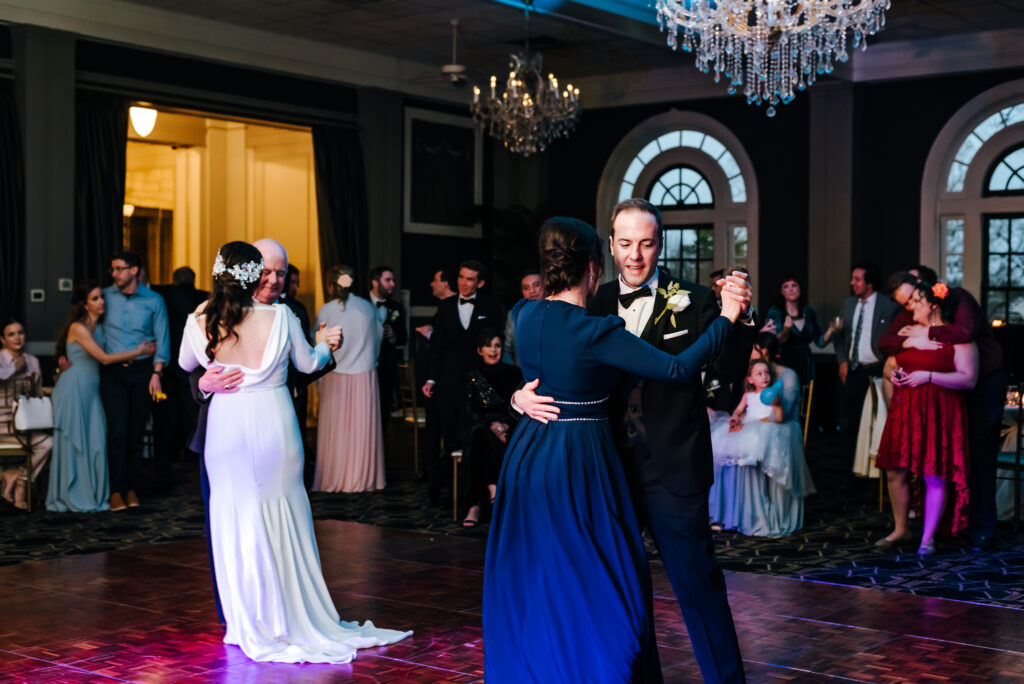 The groom dances with his mother, and his father asks his bride to dance