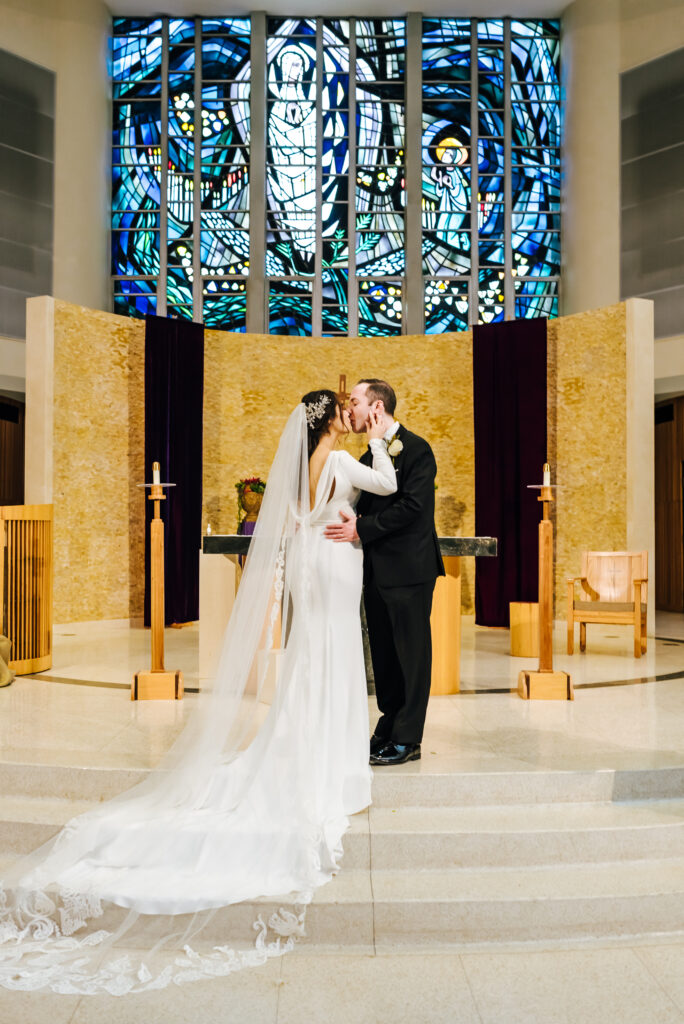 The bride and groom share a kiss at the altar