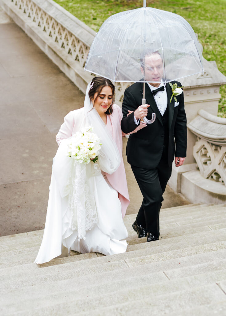 Another perspective of the newlyweds walking up the stairs with their umbrella