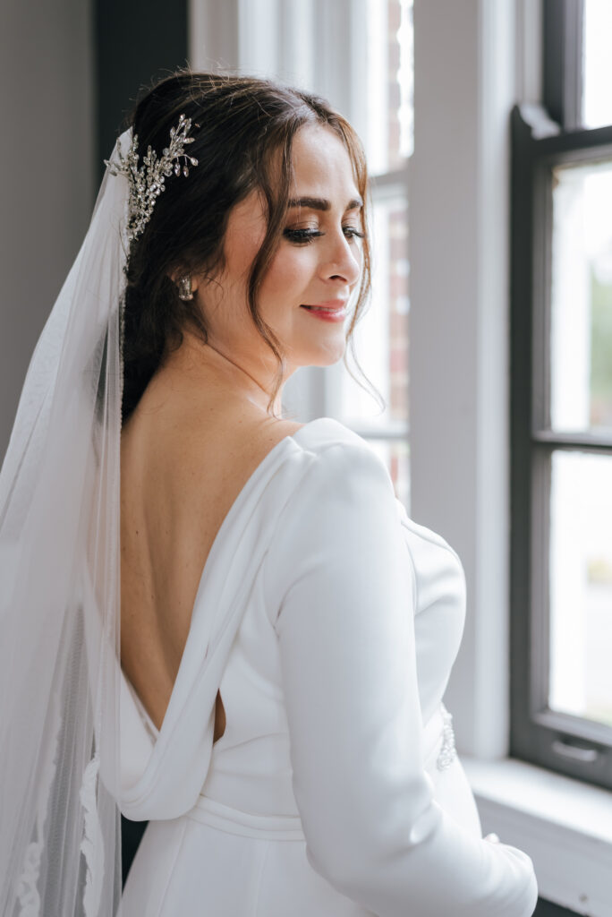 The stunning bride wears a long sleeved Paloma Blanca dress