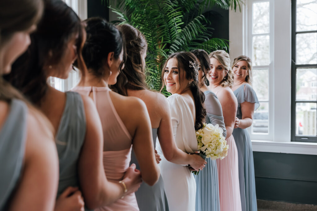 The bride is in the center of her bridesmaids and smiles at them