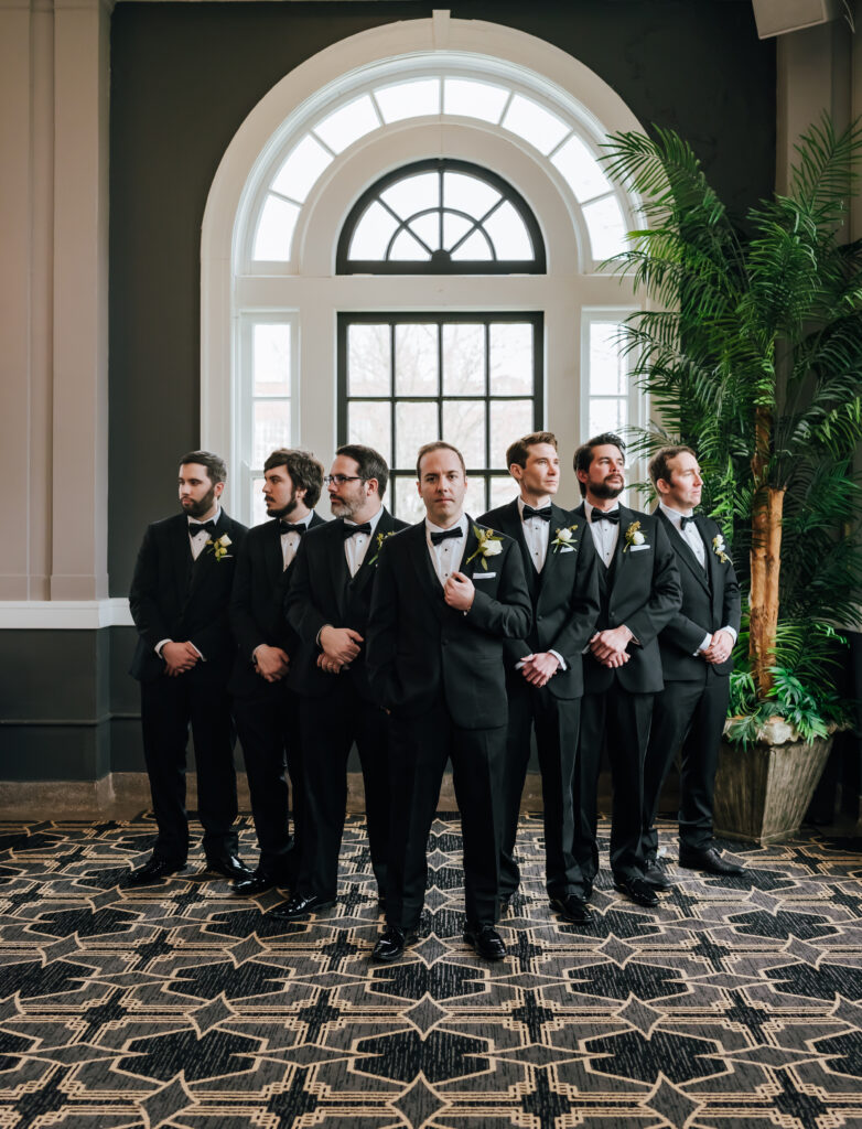The groom and his groomsmen pose in a V formation