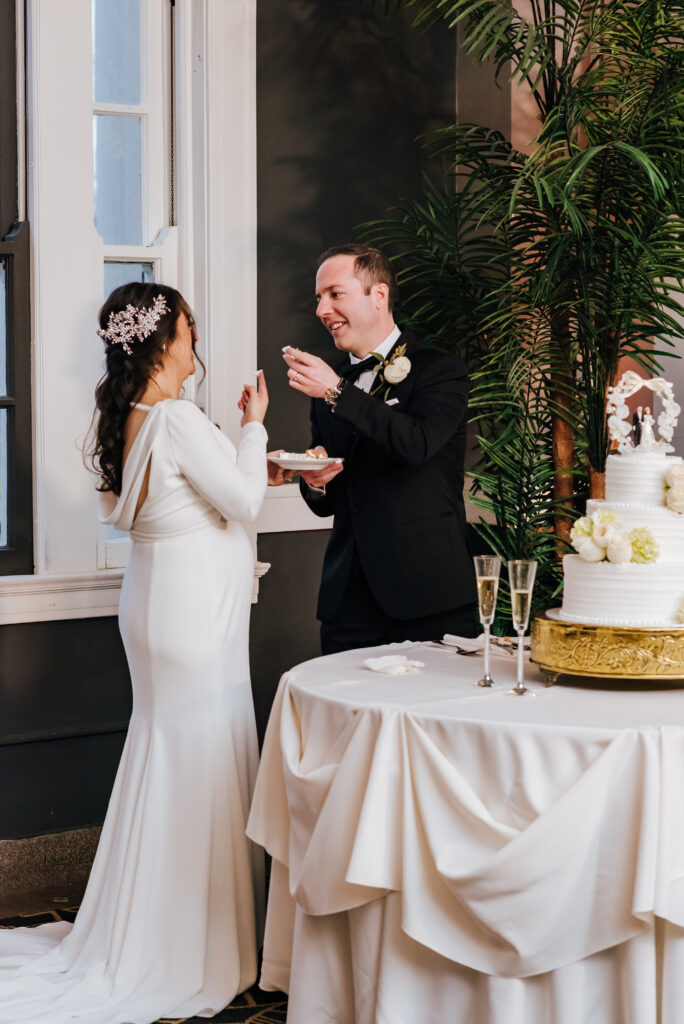 The bride and groom raise their forks to feed each other a slice of their delicious wedding cake
