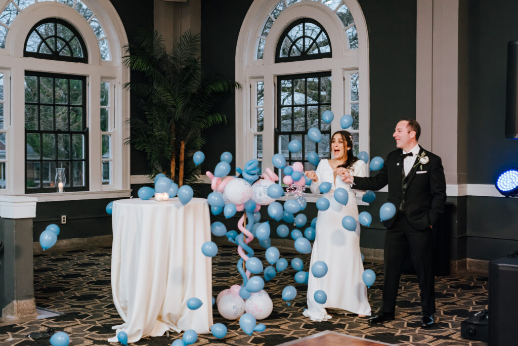 The balloon explodes, releasing dozens of tiny blue balloons in a gender reveal surprise