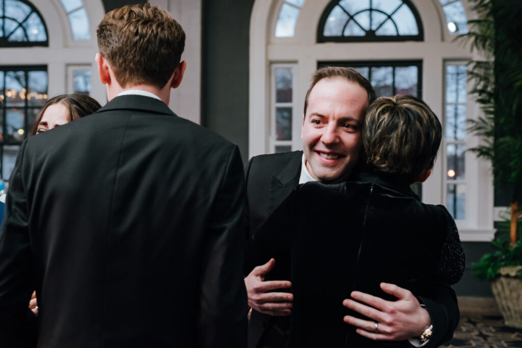 The groom hugs his family with excitement