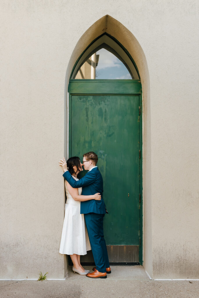 The newlyweds share a kiss in front of a tall green door