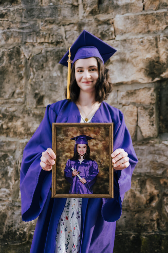 A graduate holds her elementary school graduation photo as she wears her cap and gown.