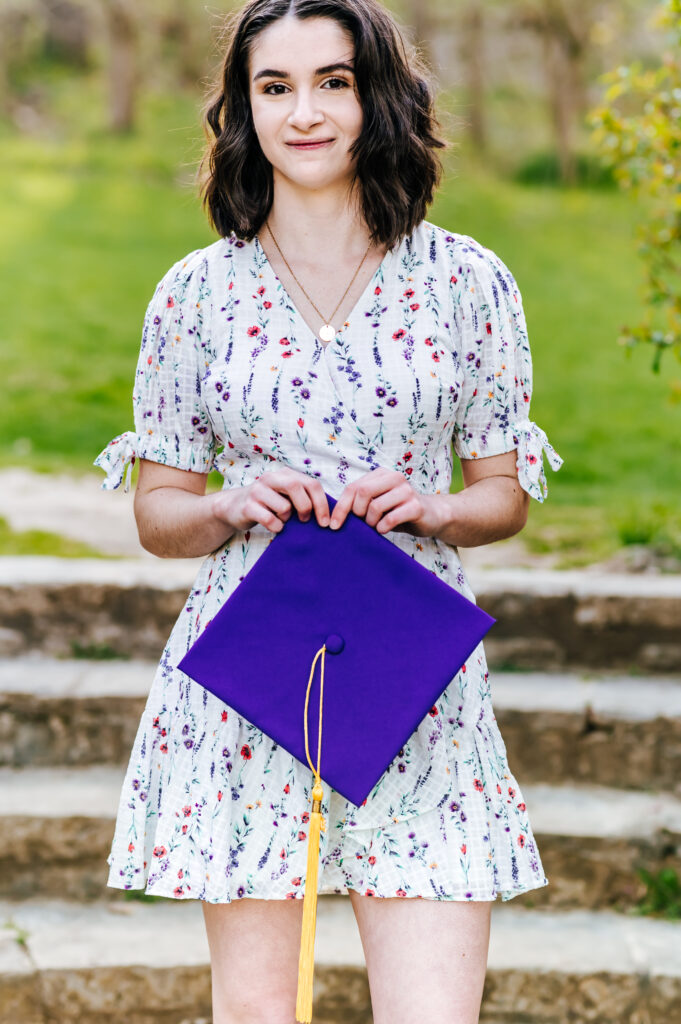 A graduate poses with her purple cap and gown