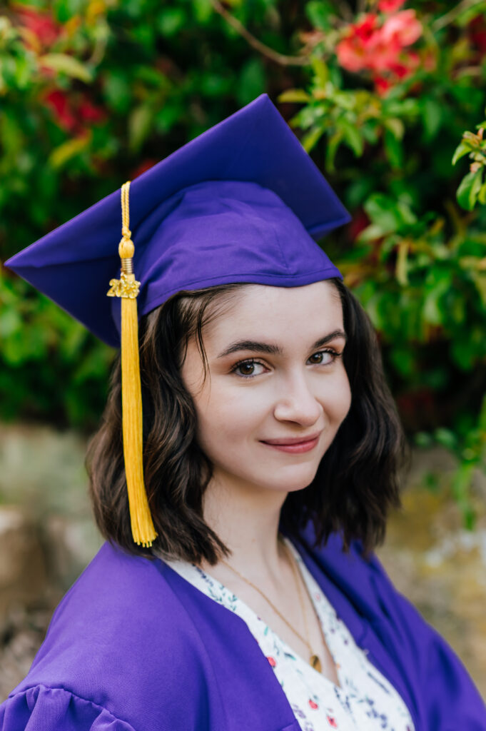 A graduate in a purple cap and gown looks into the distance