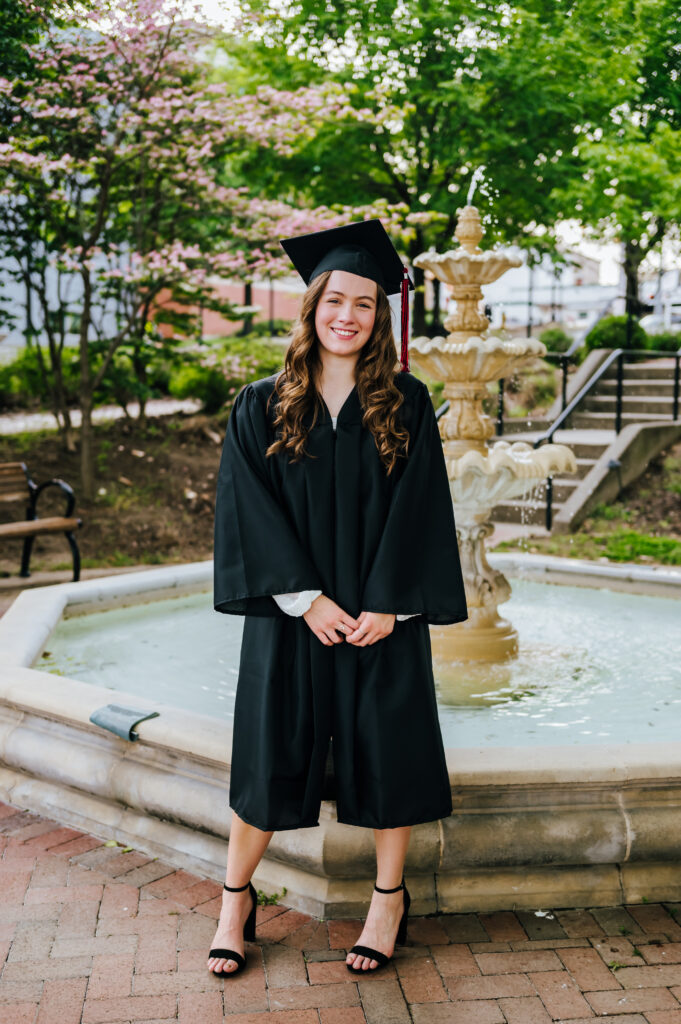 A high school senior wears her school graduation attire and smiles for a portrait