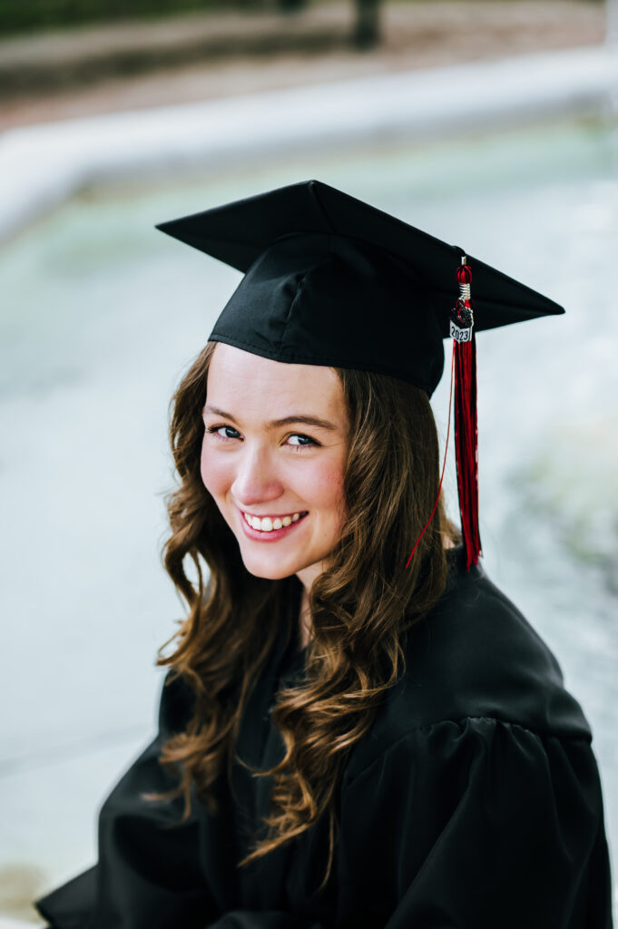 A high school senior wears her school graduation attire and smiles for a close up portrait