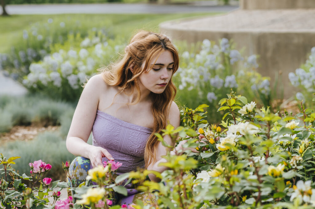 A girl crouches down to admire the wildflowers