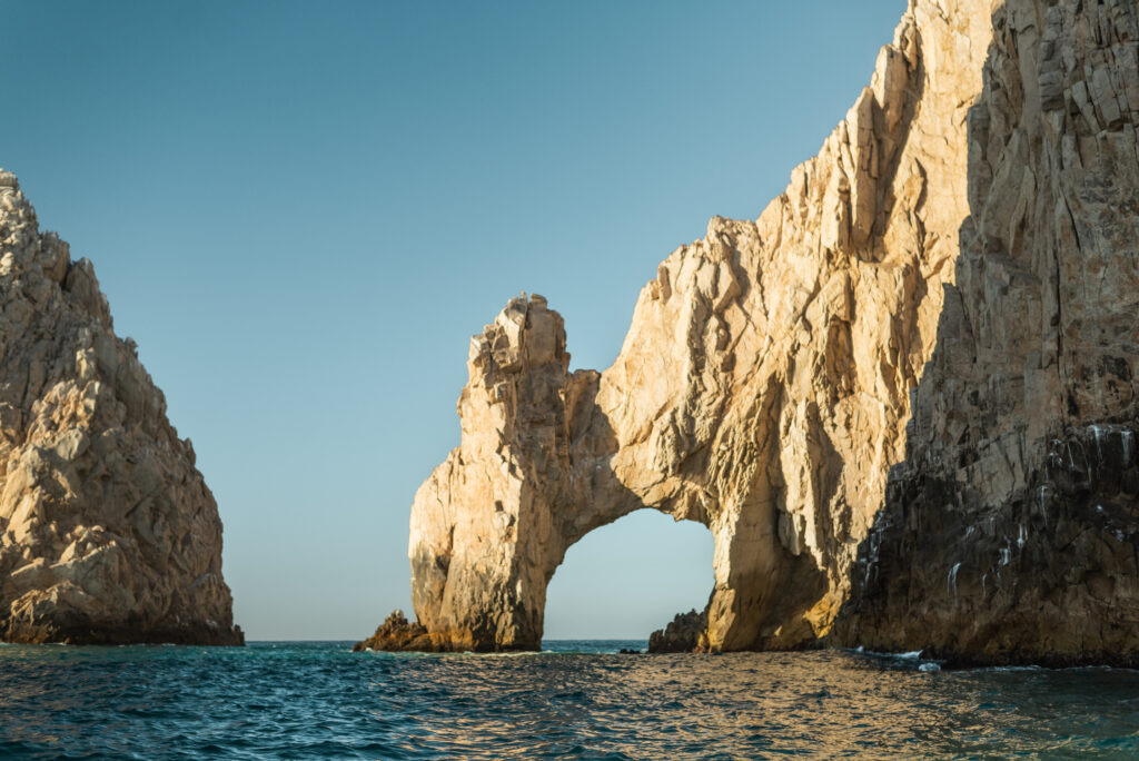 A photograph of an iconic arch in Cabo San Lucas over the blue ocean