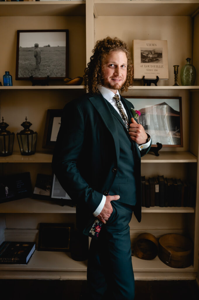 A curly-haired groom sports an emerald green suit on his wedding day