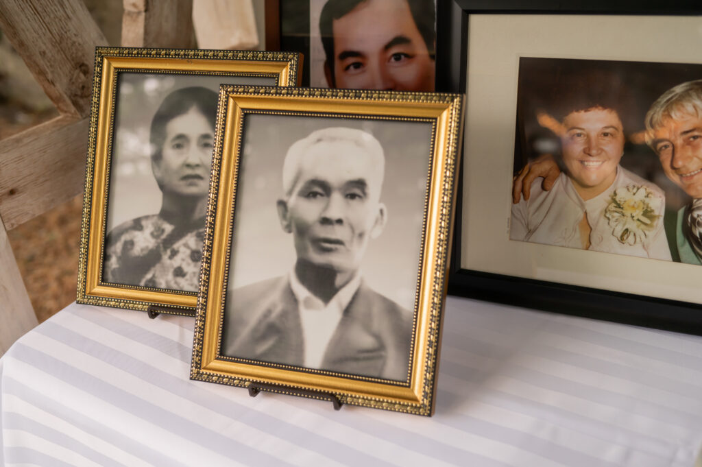 Several framed photographs (some black and white, some color) decorate a table to honor deceased ancestors