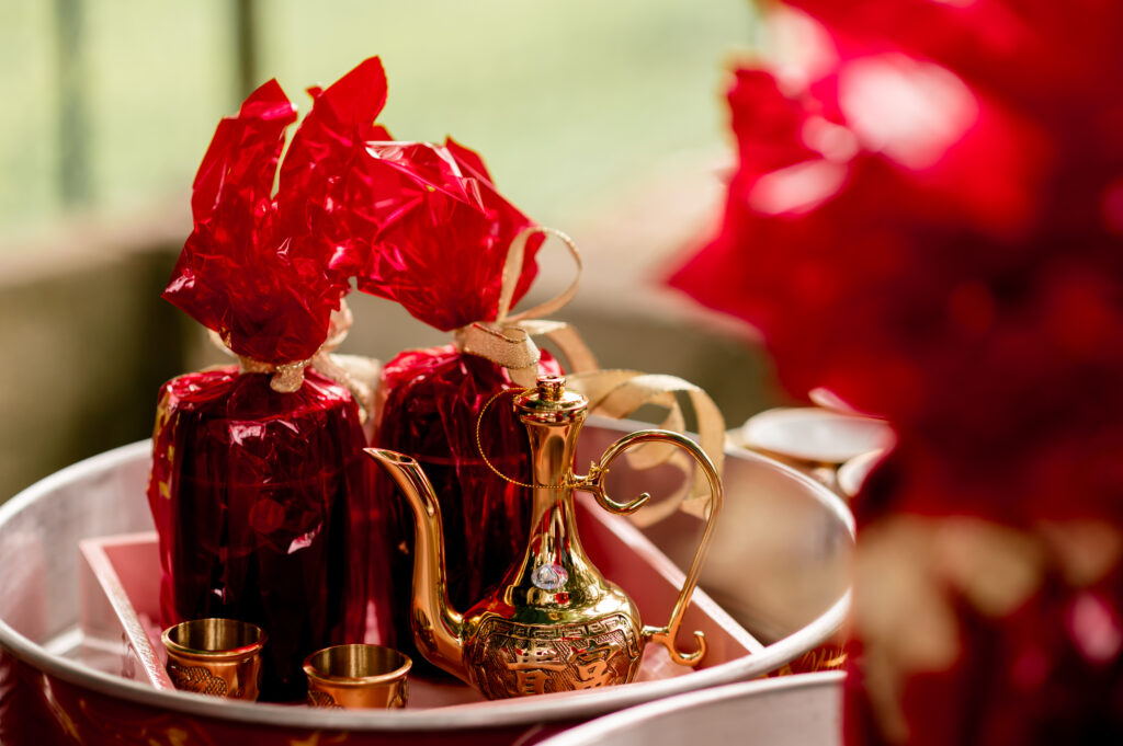 A golden tea kettle sits in a tray with gifts wrapped in red cellophane