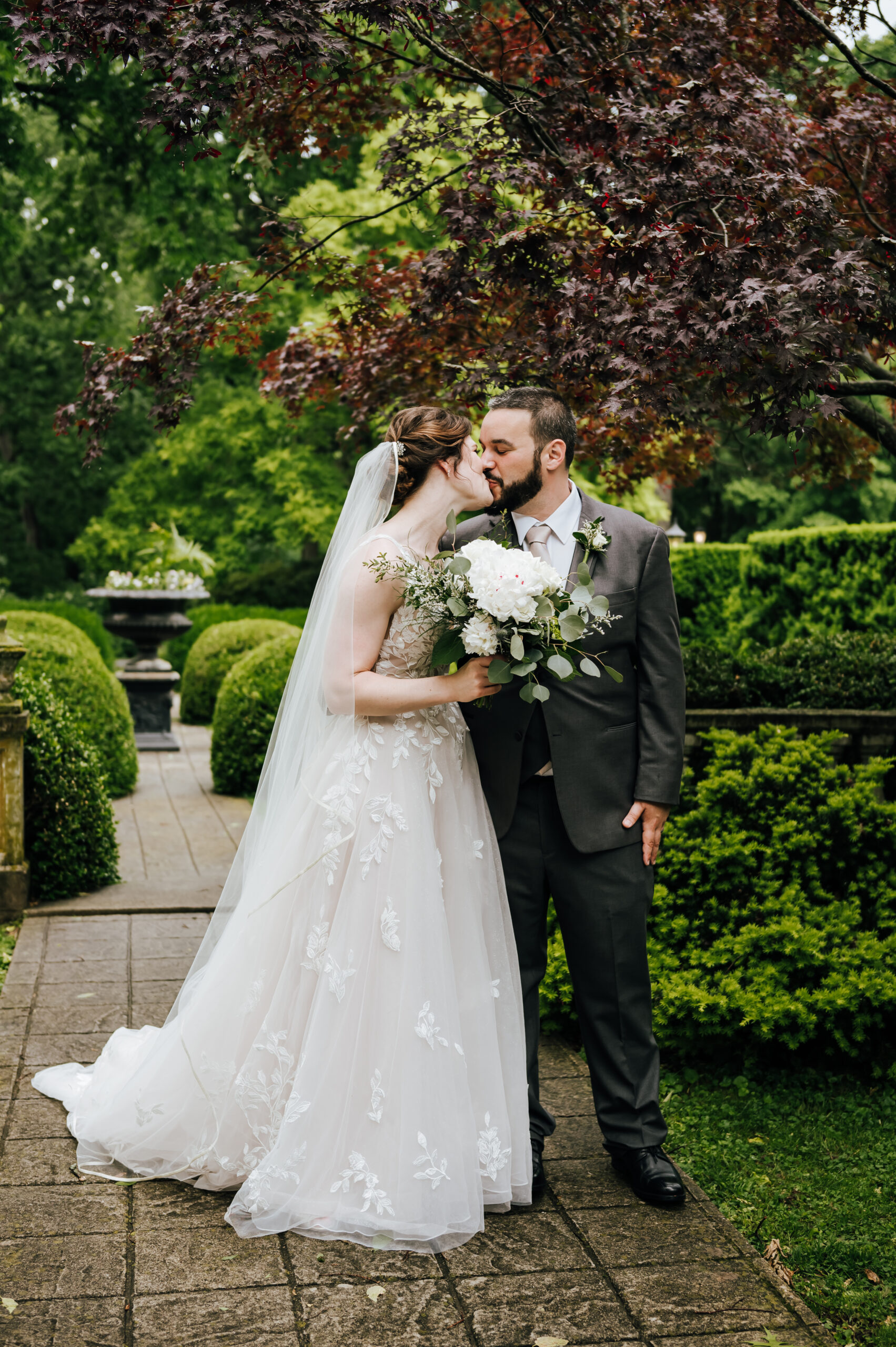 The newlyweds share a kiss in the lush green gardens of Whitehall Mansion