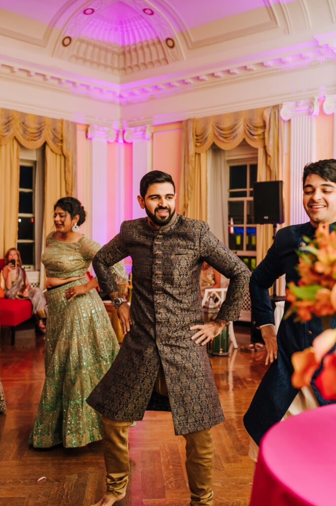 The groom places his hands on his hips as he dances to a choreographed performance