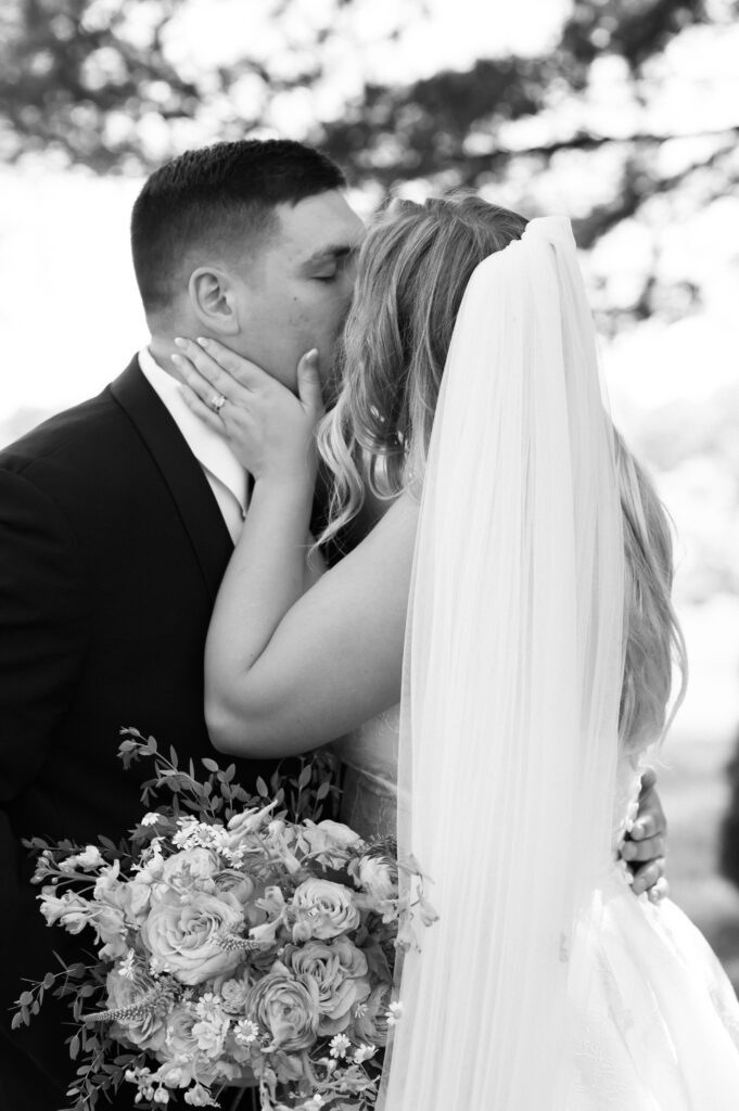 A black and white photo of a couple as they embrace for a kiss 