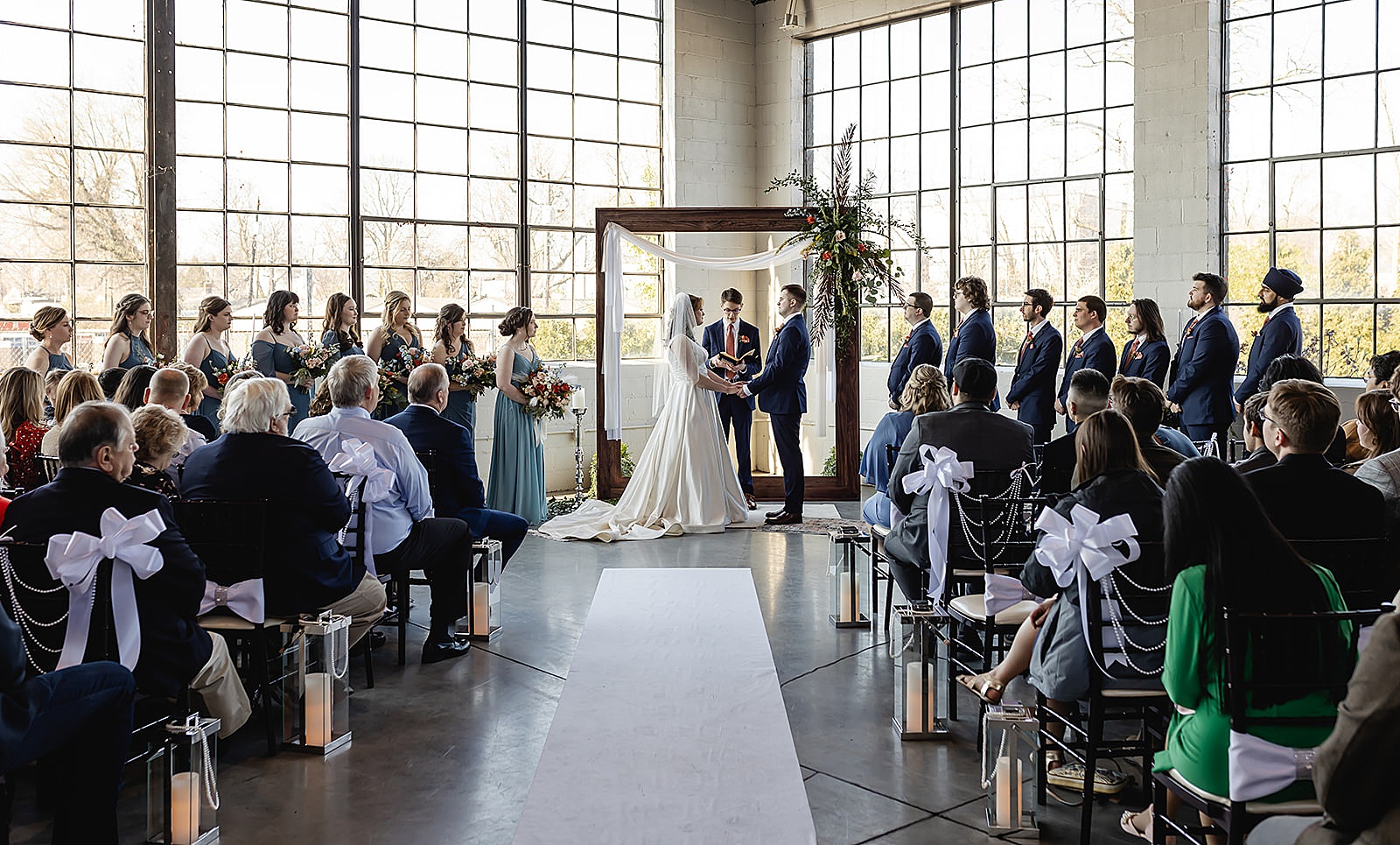 A bride and groom stand beneath an arch in an industrial Louisville wedding venue.