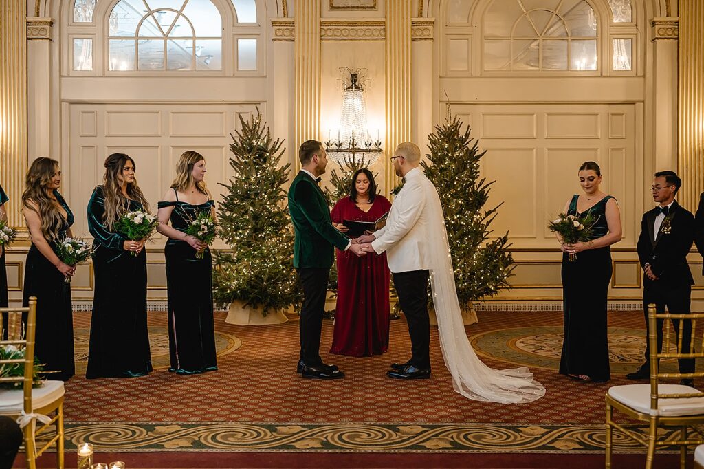 Two grooms hold hands during a wedding inside the Brown Hotel in Louisville.