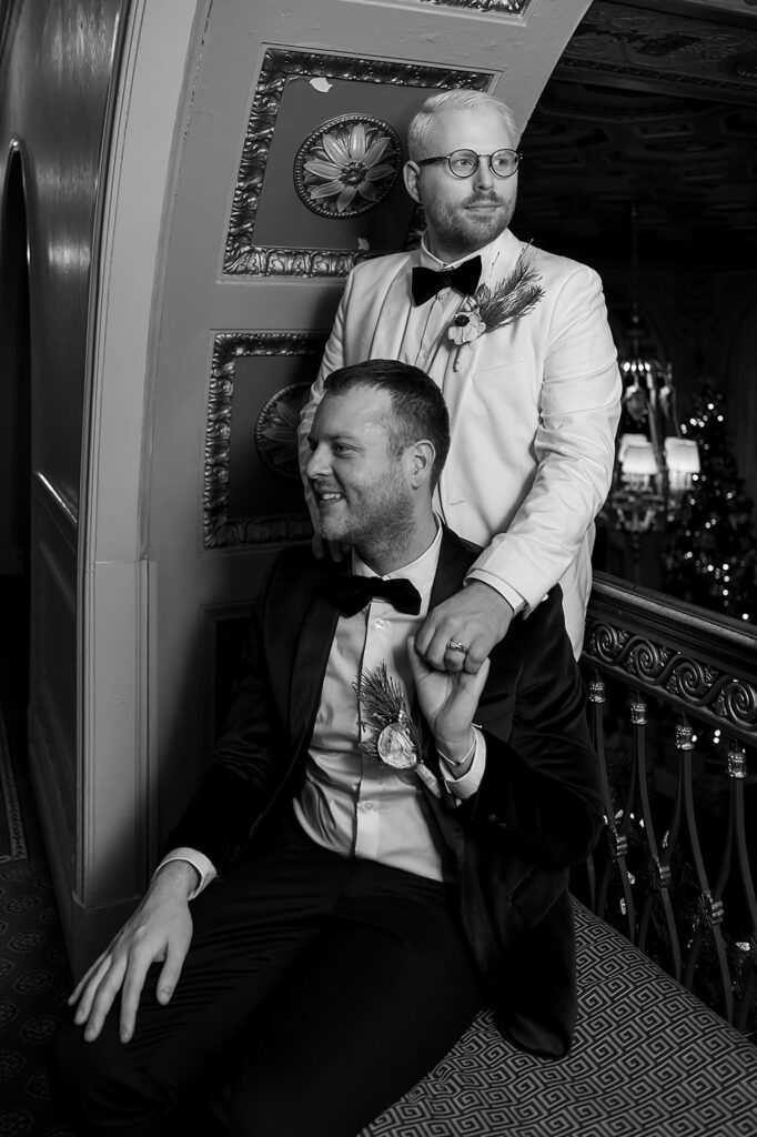 Two grooms pose for a Louisville wedding photographer on a hotel balcony.