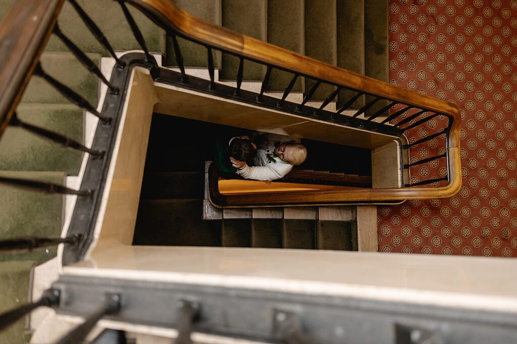 Two grooms stand in an old-fashioned staircase.