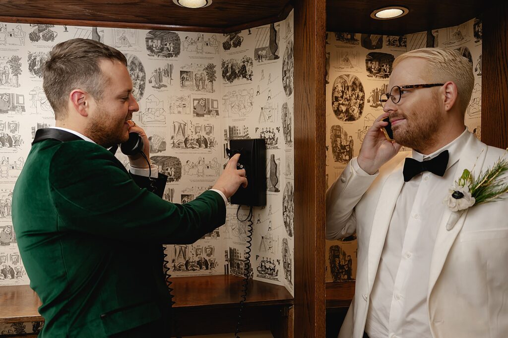 Two grooms pose in a vintage phone booth in the Brown Hotel Louisville.