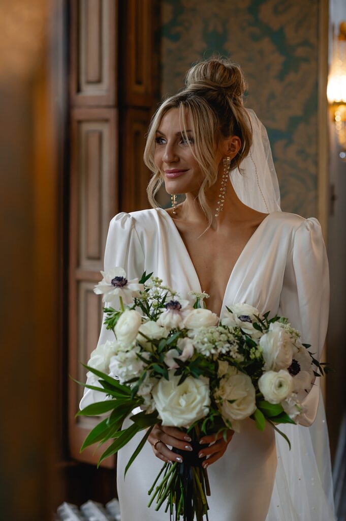 A bride in a modern wedding dress poses with a bouquet in a Louisville wedding venue.