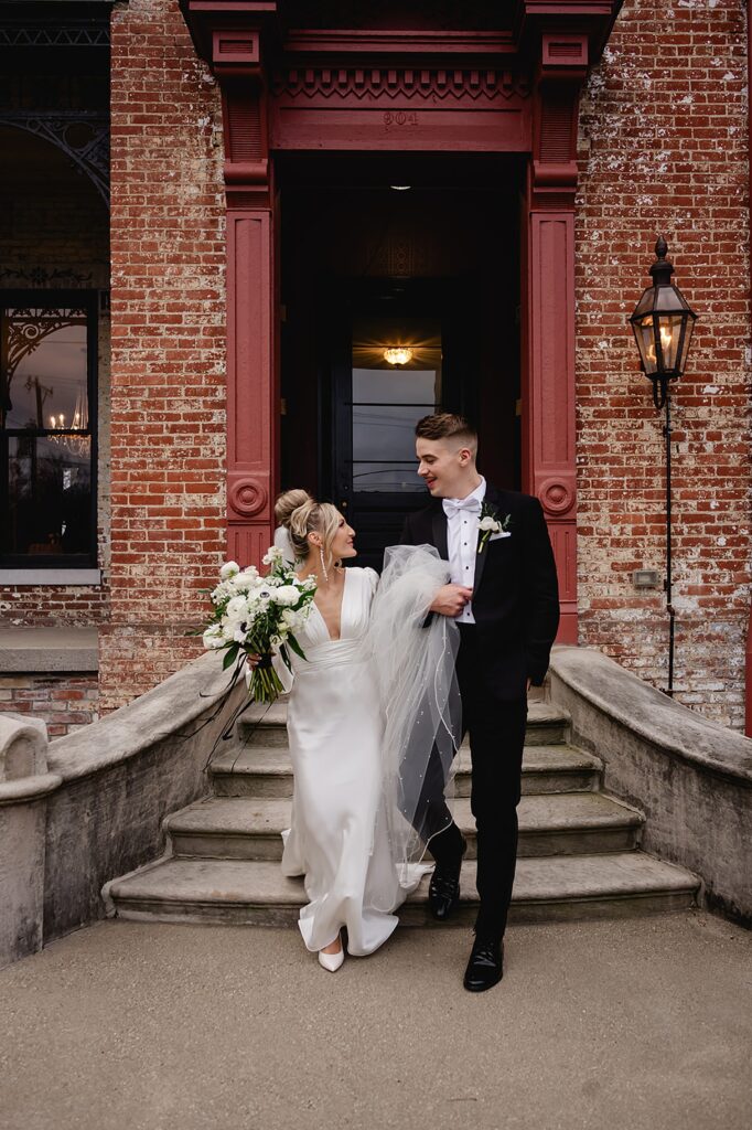 A bride and groom walk down a staircase outside a wedding venue in Louisville.